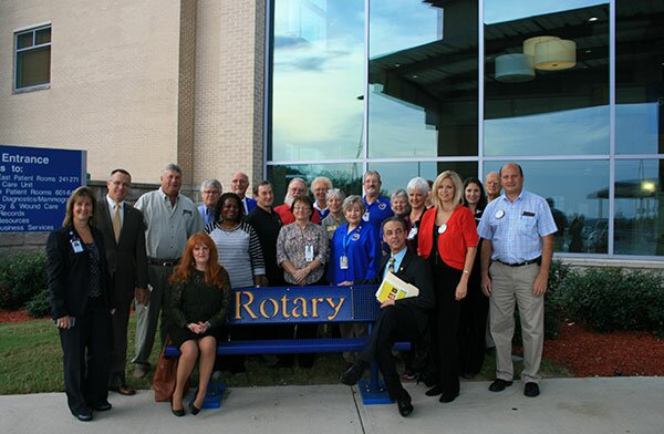 Deborah Armstrong, CEO of Rockdale Medical Center (left) shows appreciation for the recent donation of benches from the Rotary Club of Rockdale County. Sitting on the bench is Immediate-Past Club President Elly Dalton and Club President Alain Bouzoubaa. Others in the photo are Rotary club members, volunteers and employees of RMC. The benches were donated so that visitors could have a place to sit & enjoy the outdoors while visiting loved ones who are receiving care at the hospital. 